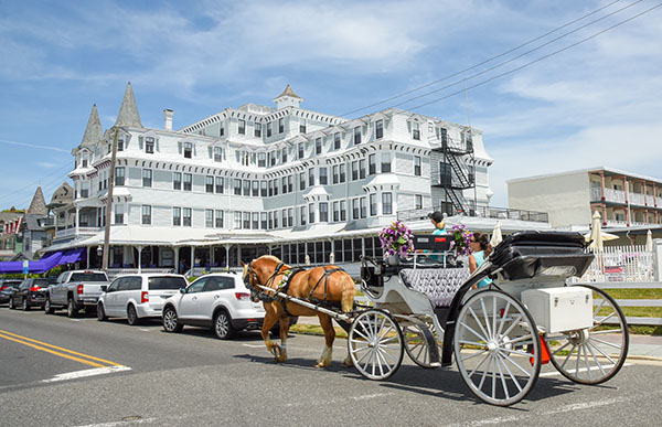 A vis-a-vis horse carriage passing the Inn of Cape May